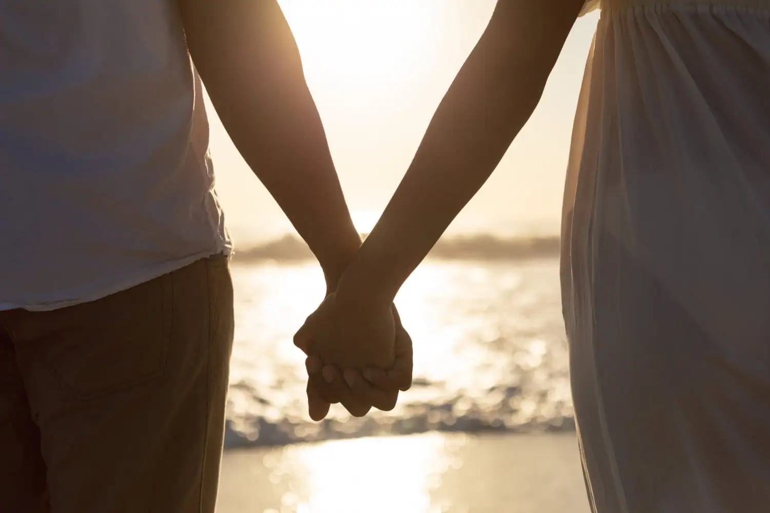 A man and woman holding hands on the beach