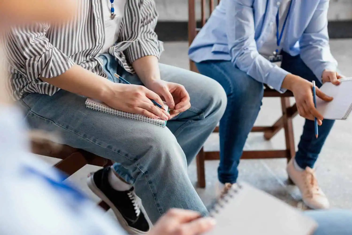 People sitting in a circle with notebooks and pens